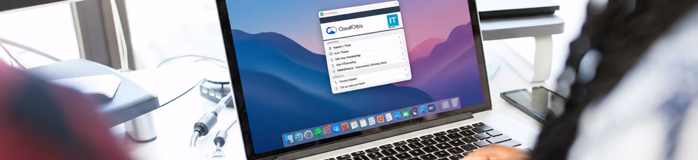 Open laptop on a desk displaying a CloudOps software interface with a blue and purple mountain wallpaper background.